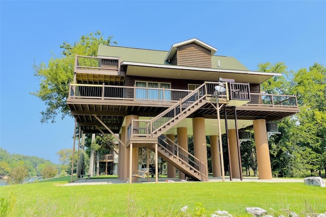 rear view of property with a yard, stairway, and a deck