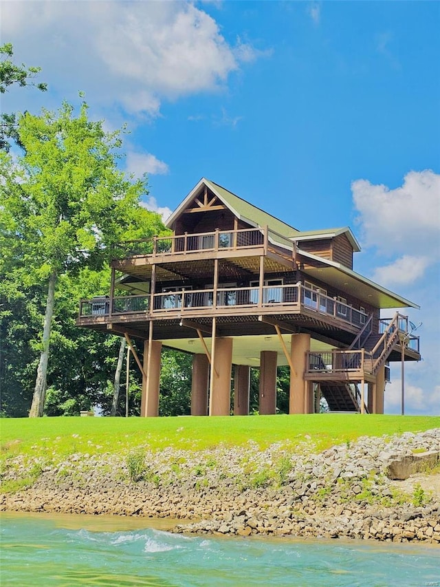 back of property featuring a deck with water view and stairway