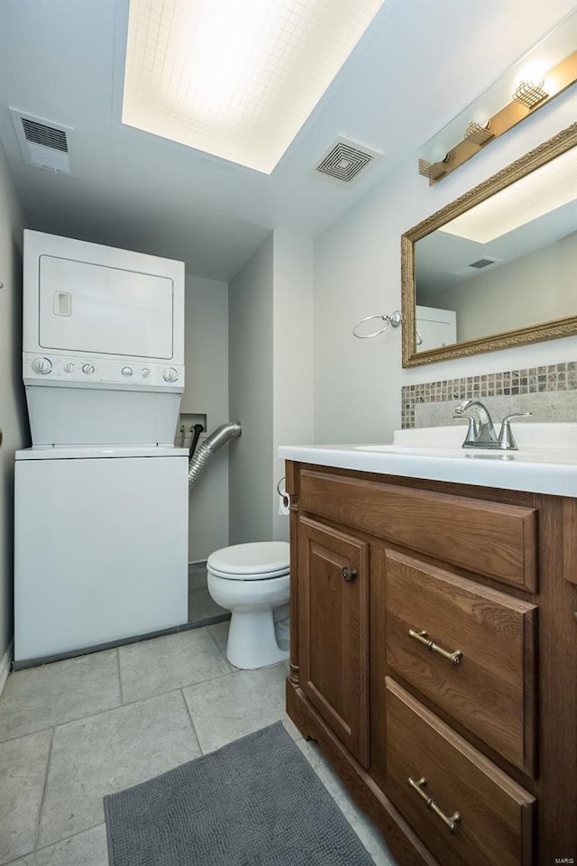 13579 Coliseum Dr Unit G, Chesterfield, MO 63017 - bathroom with estacked washer and dryer, toilet, backsplash, vanity, and tile patterned floors