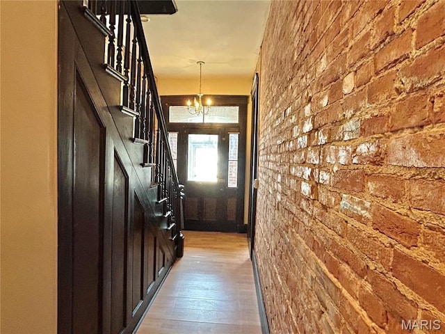 410 N Main St, Red Bud, IL 62278 - doorway to outside with stairs, light wood-style flooring, brick wall, and a chandelier