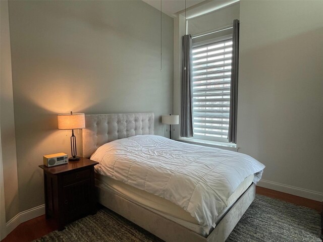 bedroom with baseboards, multiple windows, and wood finished floors