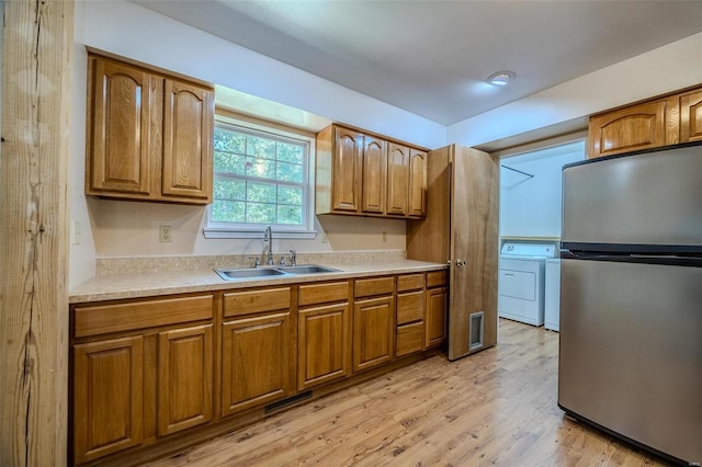 28 Acacia Dr, Conway, MO 65632 - kitchen with freestanding refrigerator, a sink, washing machine and dryer, and brown cabinetry