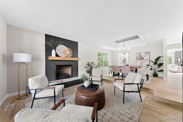 6 Freedom Way, Saint Charles, MO 63303 - living room with baseboards, light wood-type flooring, a fireplace, a tray ceiling, and a chandelier