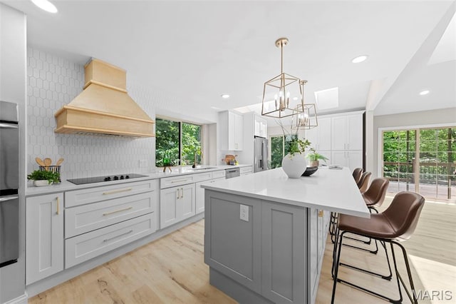 6 Freedom Way, Saint Charles, MO 63303 - kitchen with appliances with stainless steel finishes, premium range hood, a breakfast bar area, a center island, and tasteful backsplash