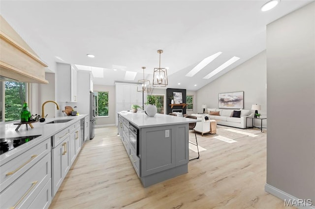 6 Freedom Way, Saint Charles, MO 63303 - kitchen featuring a sink, a skylight, a kitchen island, white cabinetry, and black electric cooktop