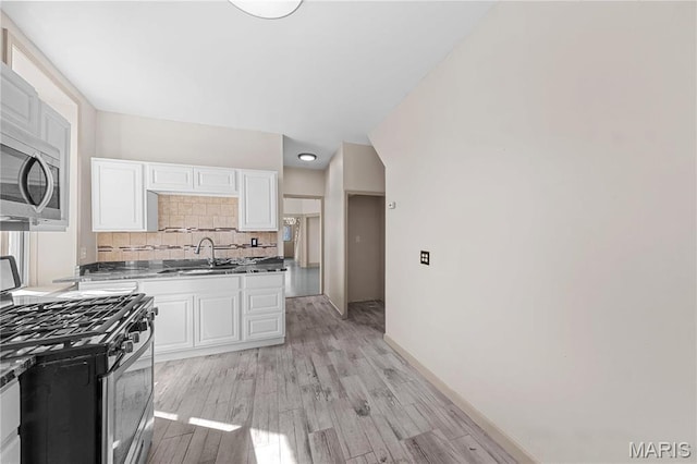 2901 Magnolia Ave, Saint Louis, MO 63118 - kitchen with stainless steel appliances, a sink, white cabinetry, and tasteful backsplash