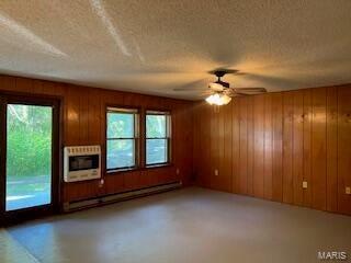 1742 Date Dr, Summersville, MO 65571 - unfurnished living room featuring heating unit, baseboard heating, healthy amount of natural light, a textured ceiling, and wooden walls