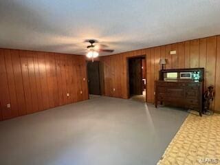 1742 Date Dr, Summersville, MO 65571 - unfurnished living room with a ceiling fan, wooden walls, and concrete floors
