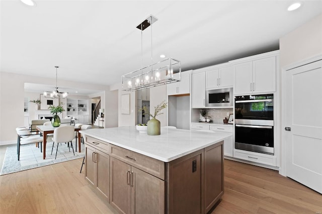 1315 Breezeridge Dr, Saint Louis, MO 63131 - kitchen with white cabinets, an inviting chandelier, stainless steel appliances, and tasteful backsplash