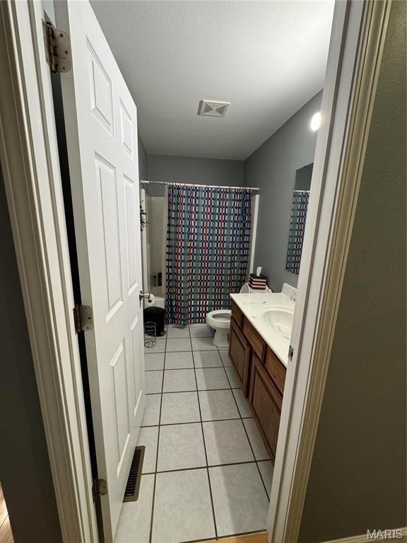 bathroom featuring toilet, vanity, tile patterned floors, and shower / bath combination with curtain