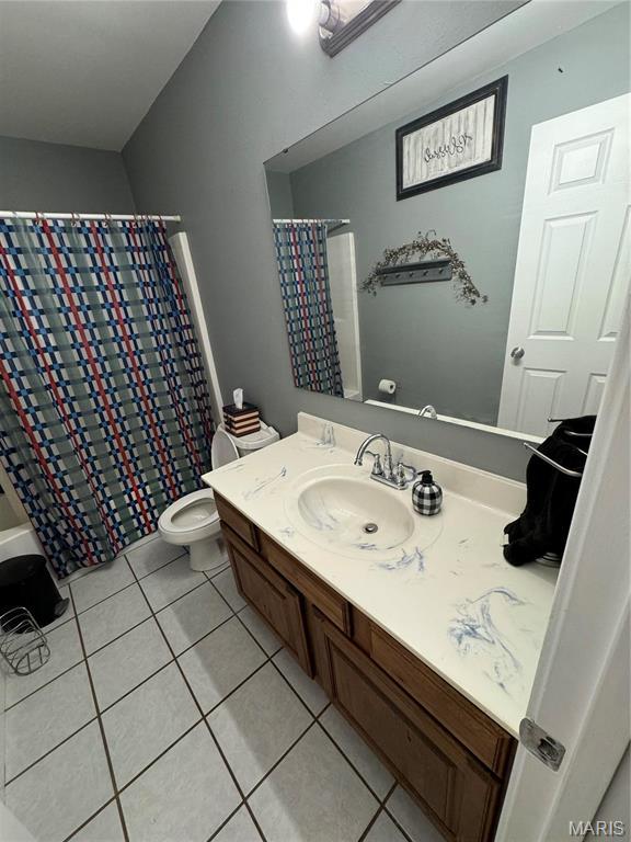 bathroom featuring tile patterned flooring, vanity, toilet, and curtained shower