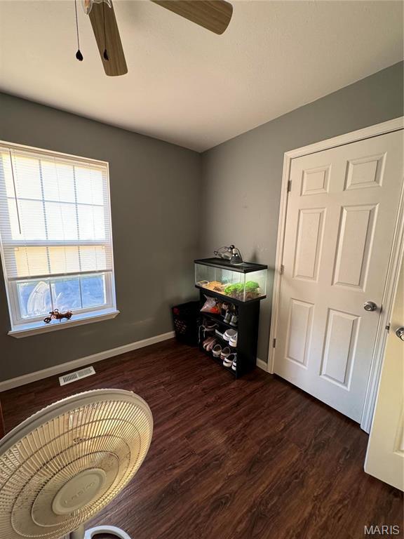 misc room featuring ceiling fan, baseboards, and dark wood-type flooring
