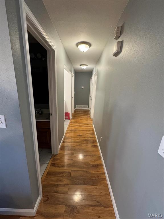 corridor with wood finished floors and baseboards