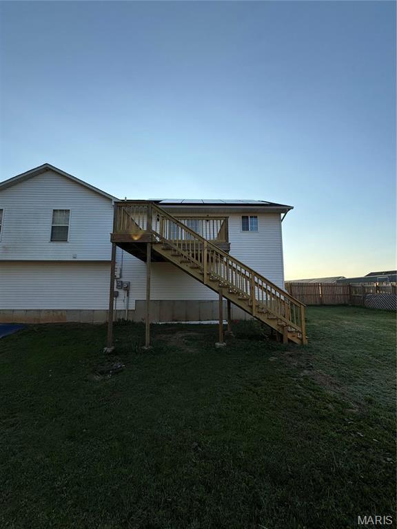 back of property at dusk with stairway and a wooden deck