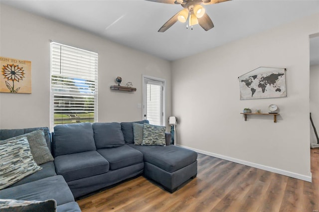 living area with a ceiling fan, dark wood-type flooring, and baseboards