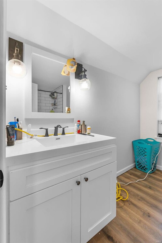 full bathroom with wood finished floors, vanity, lofted ceiling, a shower, and baseboards