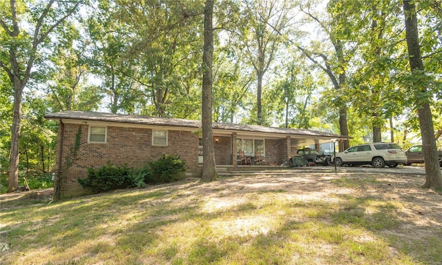 view of front of property featuring brick siding, a carport, and a front lawn