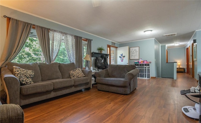 living area with wood finished floors, ornamental molding, and healthy amount of natural light