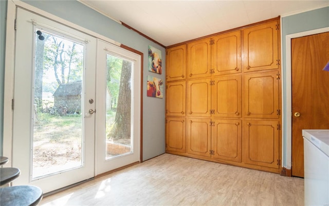 doorway to outside featuring healthy amount of natural light, light wood-style flooring, and crown molding