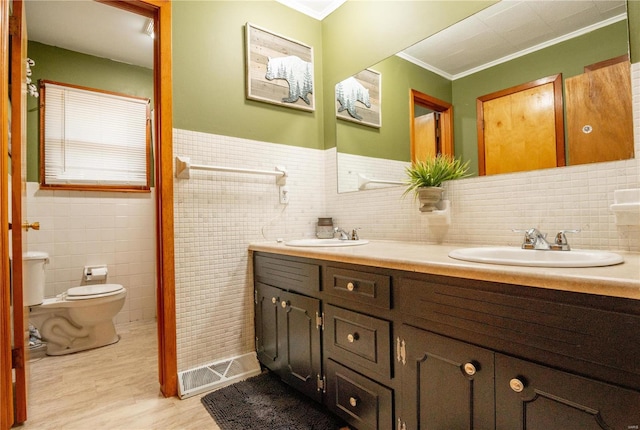 bathroom with ornamental molding, tile walls, toilet, wood finished floors, and double vanity