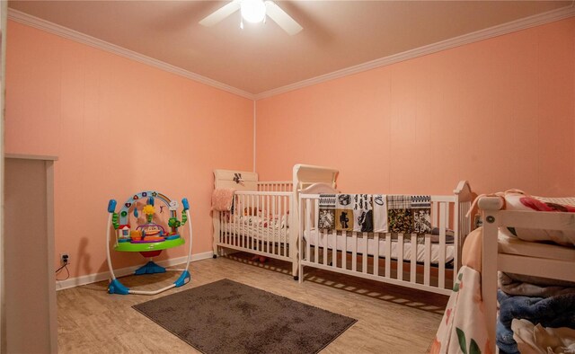 bedroom with ornamental molding, a crib, a ceiling fan, and baseboards