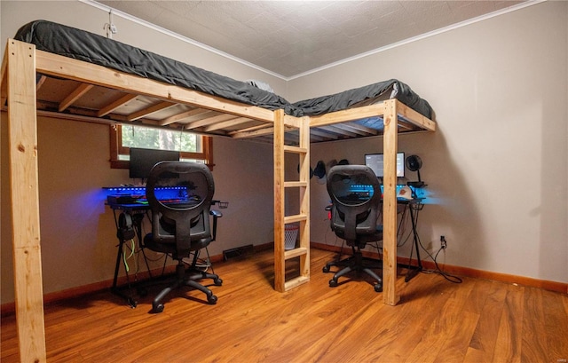 bedroom with crown molding, wood finished floors, and baseboards