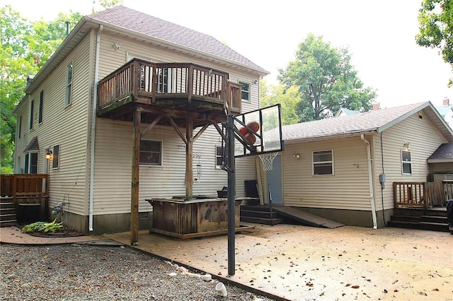 rear view of house with a patio, a deck, and a shingled roof