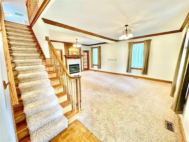 staircase featuring a chandelier, ornamental molding, baseboards, a tiled fireplace, and carpet flooring