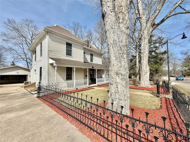 view of front of home featuring a porch, an outdoor structure, a fenced front yard, and roof with shingles