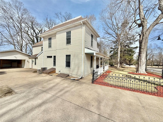 view of home's exterior featuring central AC unit, fence, a detached garage, roof with shingles, and concrete driveway