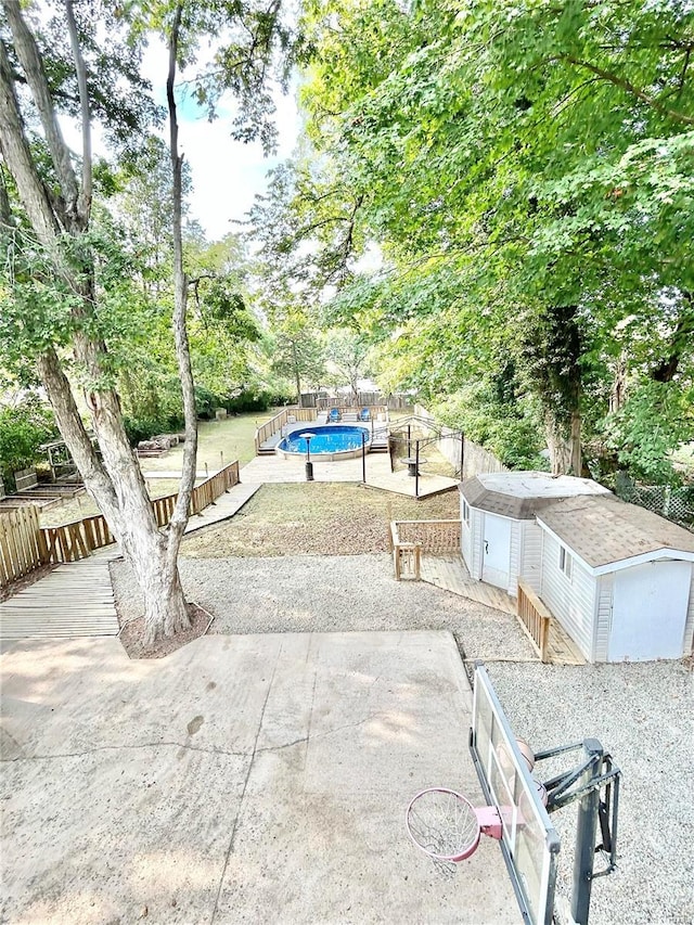 view of property's community featuring a pool, a storage unit, fence, and an outbuilding