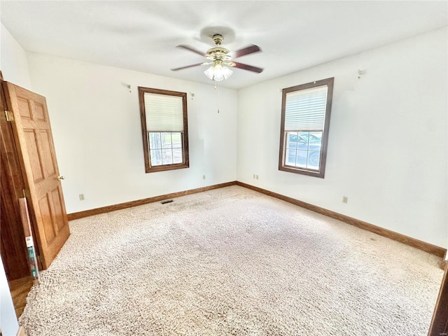 empty room featuring light colored carpet, ceiling fan, and baseboards