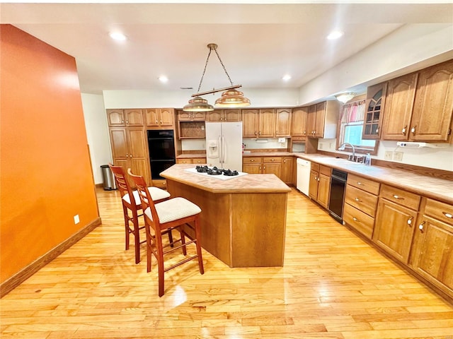 kitchen with white appliances, a kitchen bar, light wood finished floors, a center island, and light countertops