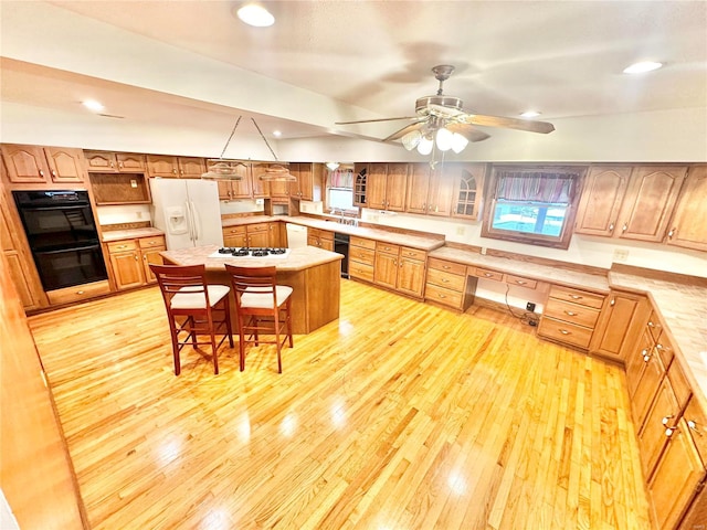 kitchen featuring white appliances, light wood-style floors, light countertops, a breakfast bar area, and recessed lighting