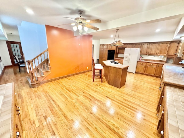 kitchen featuring white appliances, light wood finished floors, light countertops, a ceiling fan, and recessed lighting