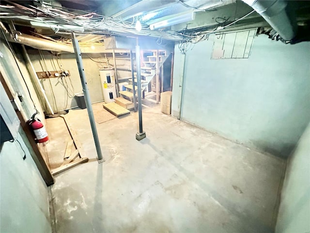 unfinished below grade area featuring electric water heater and stairway