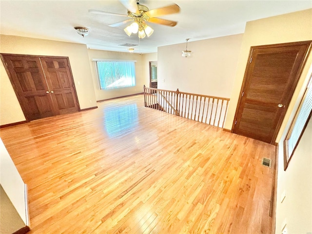empty room featuring wood finished floors, a ceiling fan, and baseboards