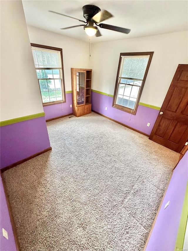 spare room featuring ceiling fan, carpet flooring, and baseboards