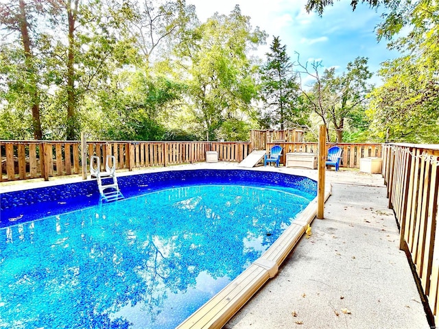 view of swimming pool with a wooden deck and view of wooded area