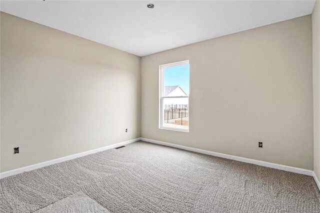 carpeted empty room featuring baseboards