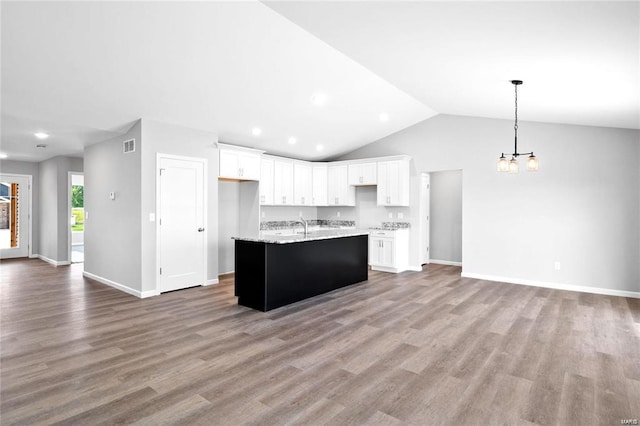 kitchen with open floor plan, a chandelier, white cabinets, light wood-style flooring, and vaulted ceiling