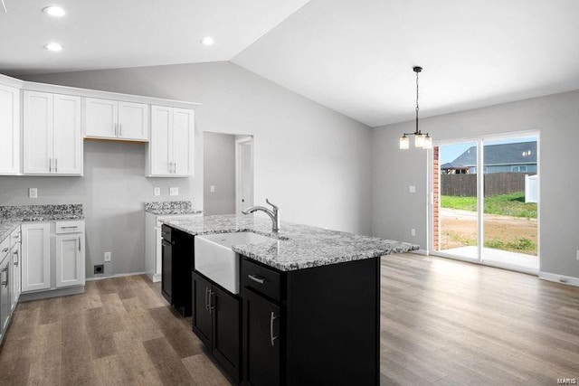kitchen with vaulted ceiling, a sink, a kitchen island with sink, white cabinets, and light wood finished floors
