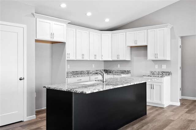 kitchen with light stone countertops, light wood-style floors, white cabinetry, recessed lighting, and lofted ceiling