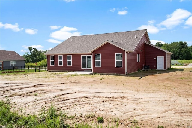 back of property with fence and a shingled roof