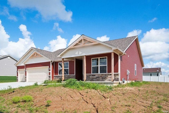 view of front of house with covered porch, a garage, stone siding, driveway, and roof with shingles