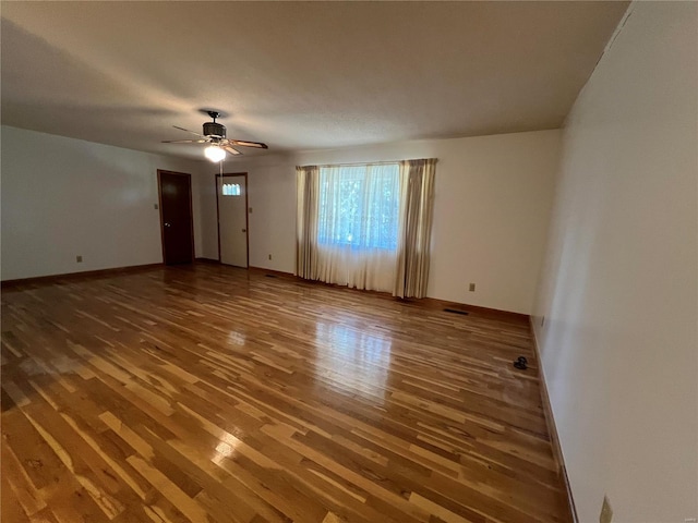 unfurnished living room with wood finished floors, a ceiling fan, and baseboards