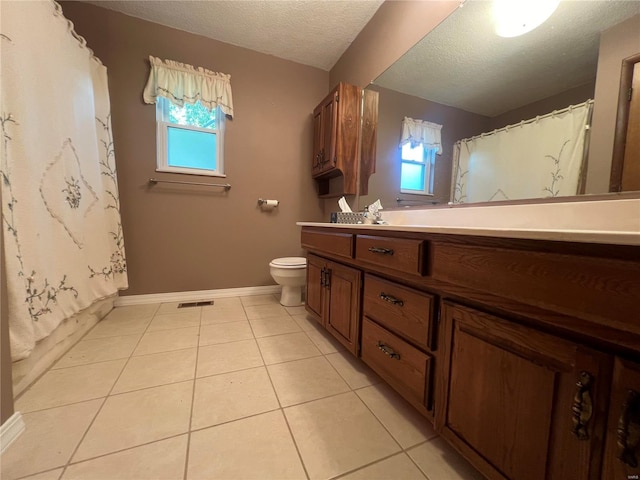 bathroom with plenty of natural light, toilet, a textured ceiling, tile patterned flooring, and vanity