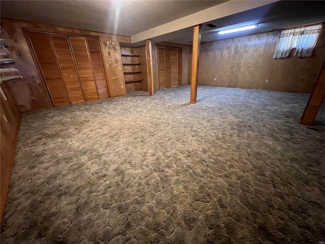 finished basement with carpet flooring, wooden walls, and a textured ceiling