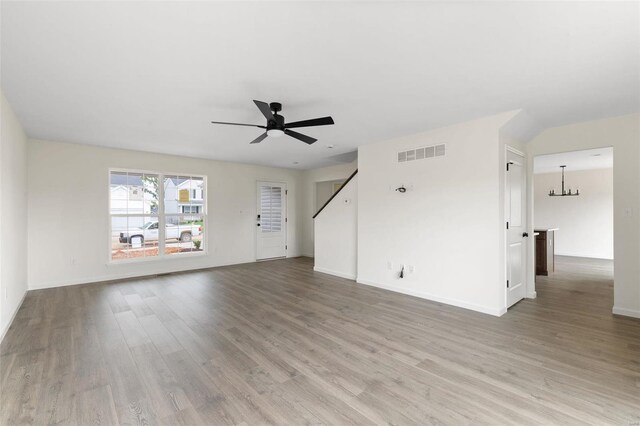 102 Harrow Dr, Ofallon, MO 63385 - unfurnished living room featuring ceiling fan, wood finished floors, a chandelier, and baseboards