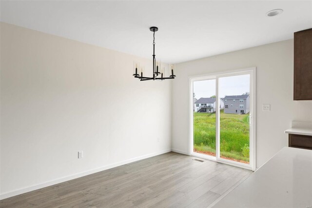 102 Harrow Dr, Ofallon, MO 63385 - unfurnished dining area with a chandelier, light wood-style flooring, and baseboards